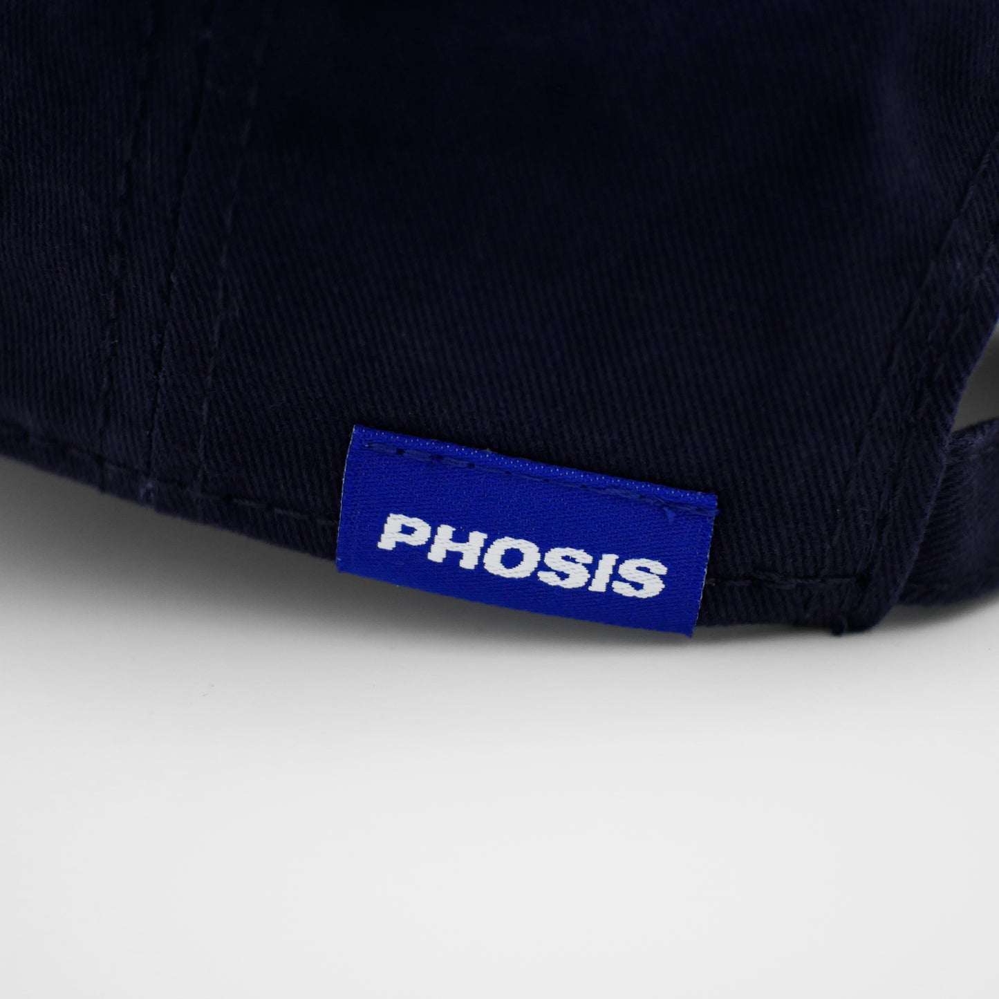 Close up view of the woven label in the ARCHETYPE black dad hat from PHOSIS® Clothing